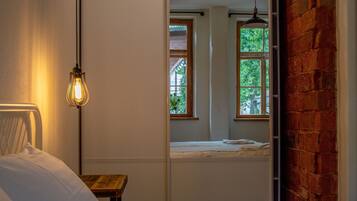 Un dormitorio con cama, lámpara colgante, ventana y pared de ladrillo.