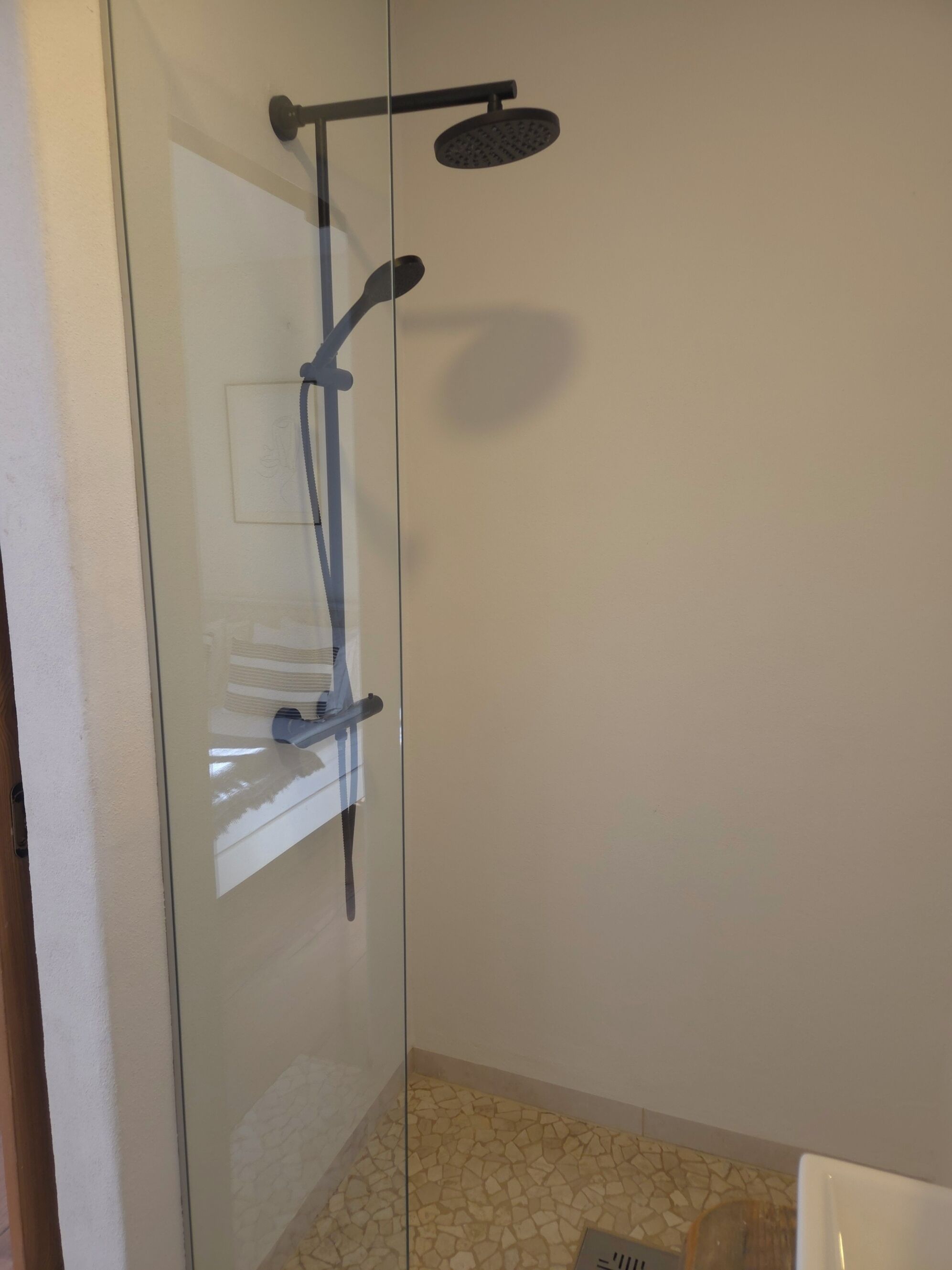 Een douchecabine van glas, met een handdouche en een inbouwregendouche.