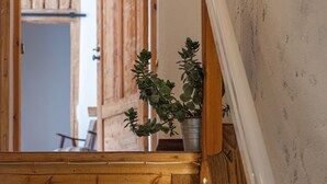 A wooden staircase with a railing, a potted plant, and a door in the background. - TAEAVS  (Võru)