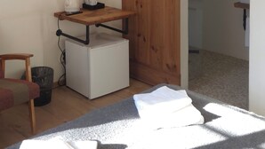 A room with a wooden wardrobe, a white radiator, a small table with a kettle and cups, a chair, and a TV mounted on the wall. - TAEAVS  (Võru)