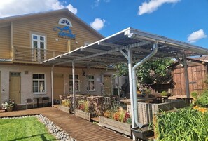 Ein Holzhaus mit einer überdachten Terrasse, Solaranlagen, Sitzgelegenheiten im Freien und einem Garten.