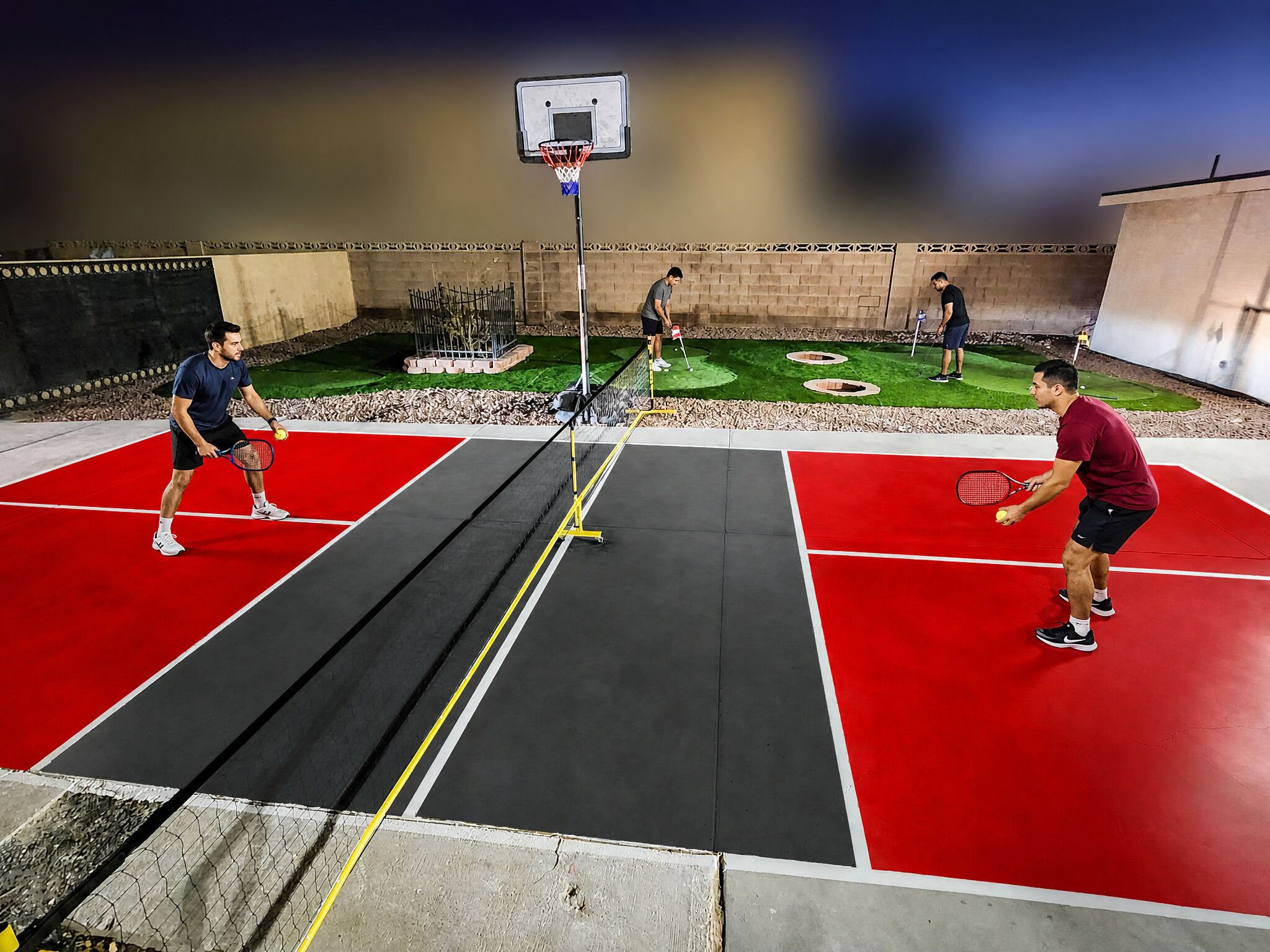 An indoor sports facility with a basketball court, tennis court, and a putting green.