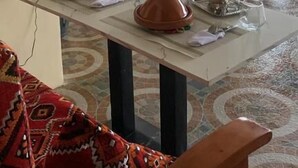 A room with a tiled floor, a ceiling fan, a table with a vase and a pitcher, and a red patterned sofa. - Morocco Hotel El Nido  (El Nido)