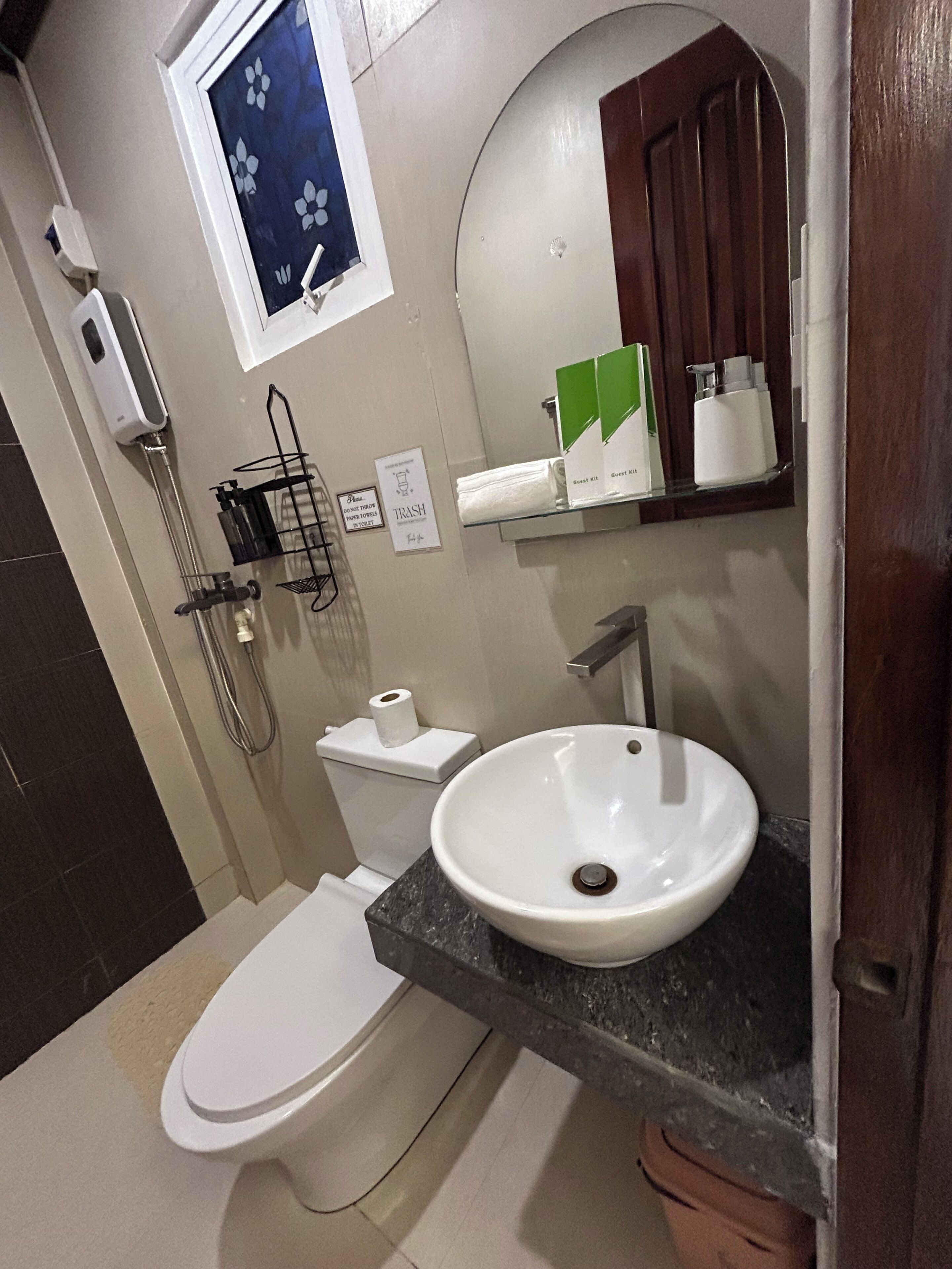 Et badeværelse med toilet, vask, brusebad og et spejl.