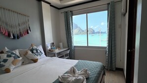 A hotel room with a bed, a desk, and a view of the sea. - Morocco Hotel El Nido  (El Nido)