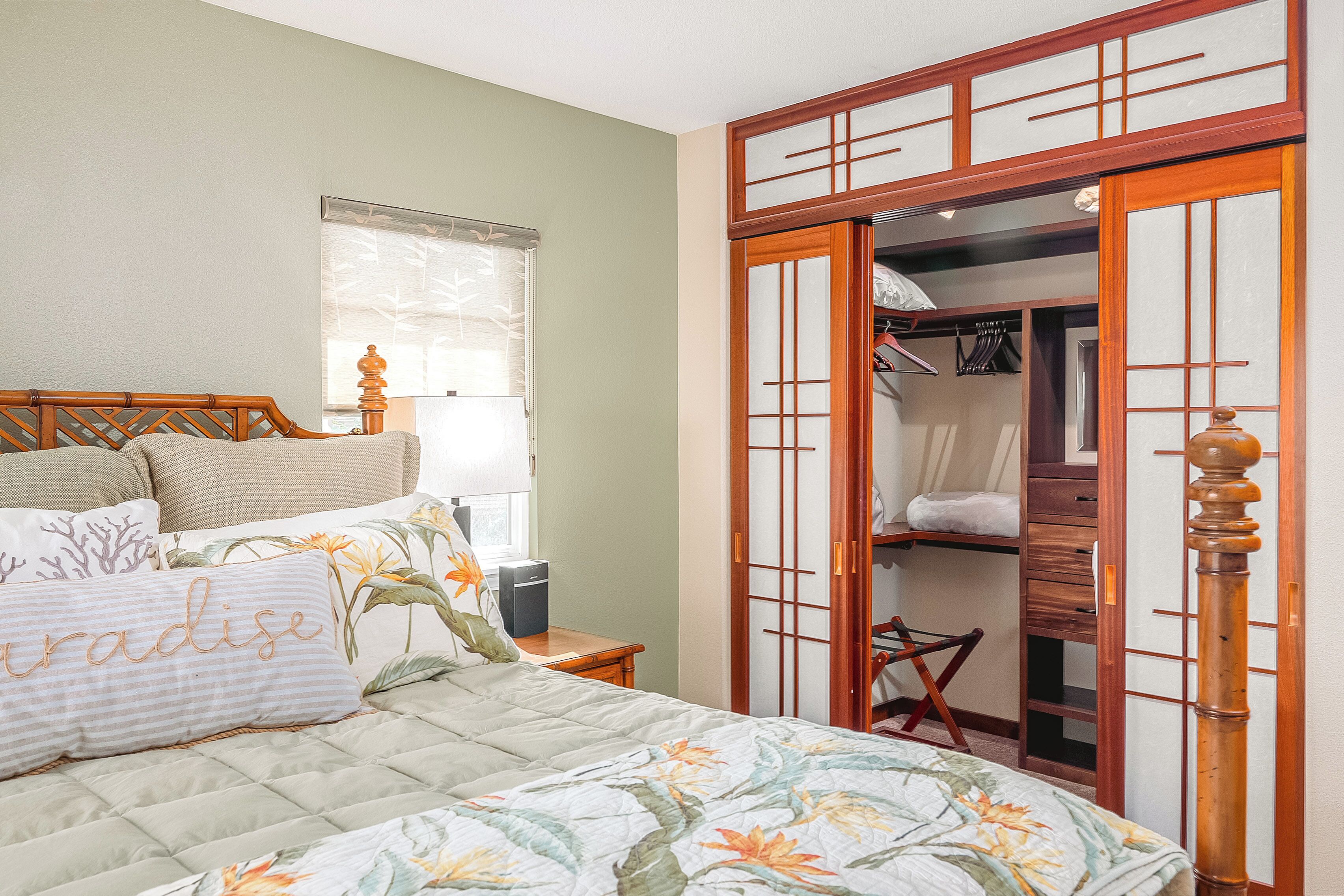 A bedroom with a bed, a nightstand, a wardrobe, and a window with blinds.
