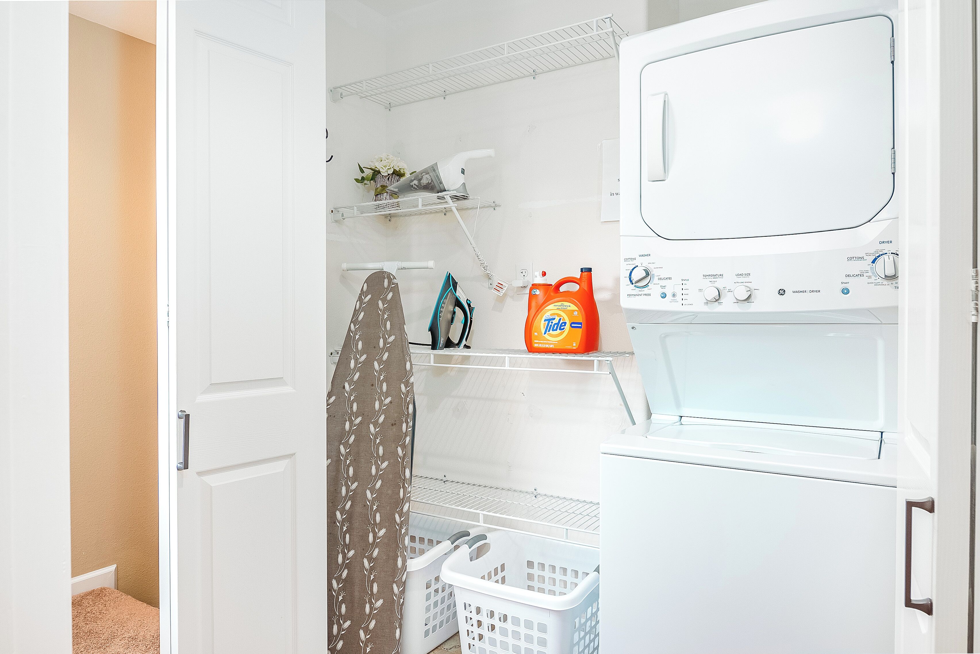 A laundry room with a washing machine, dryer, and shelves with laundry supplies.