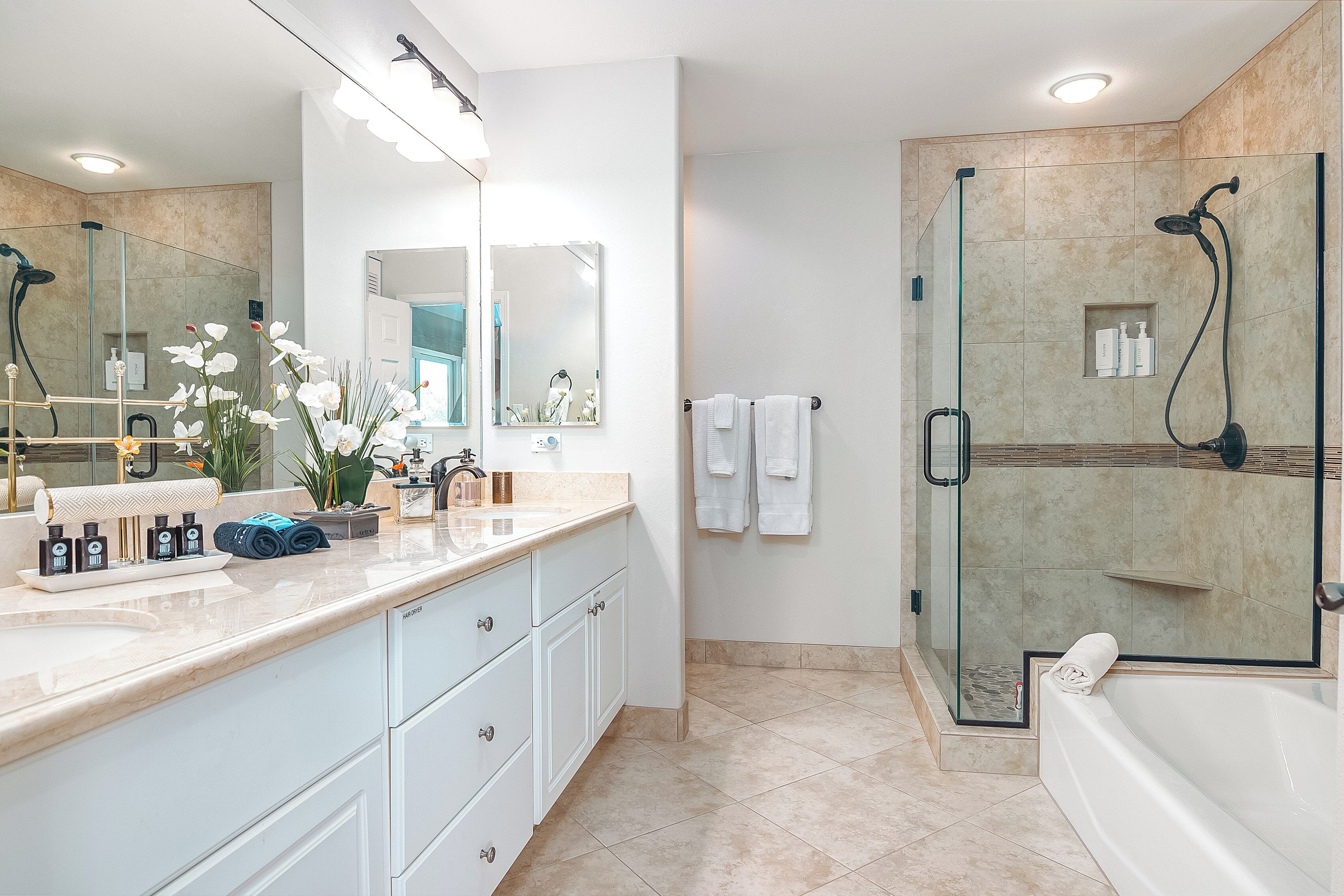 A modern bathroom with a glass-enclosed shower, a large mirror, and a bathtub.