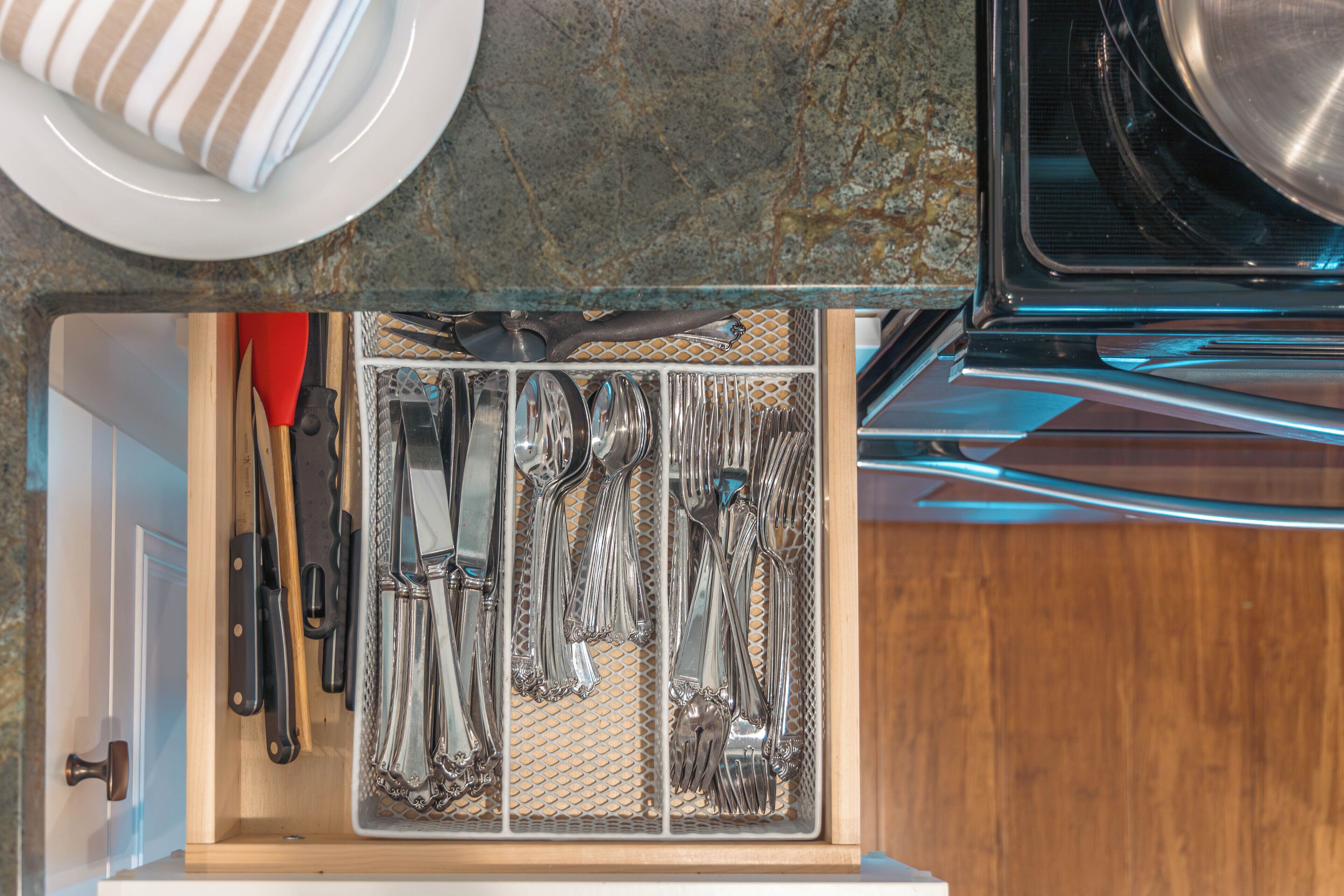 Un cajón de cocina con utensilios ordenados y un plato en la encimera.