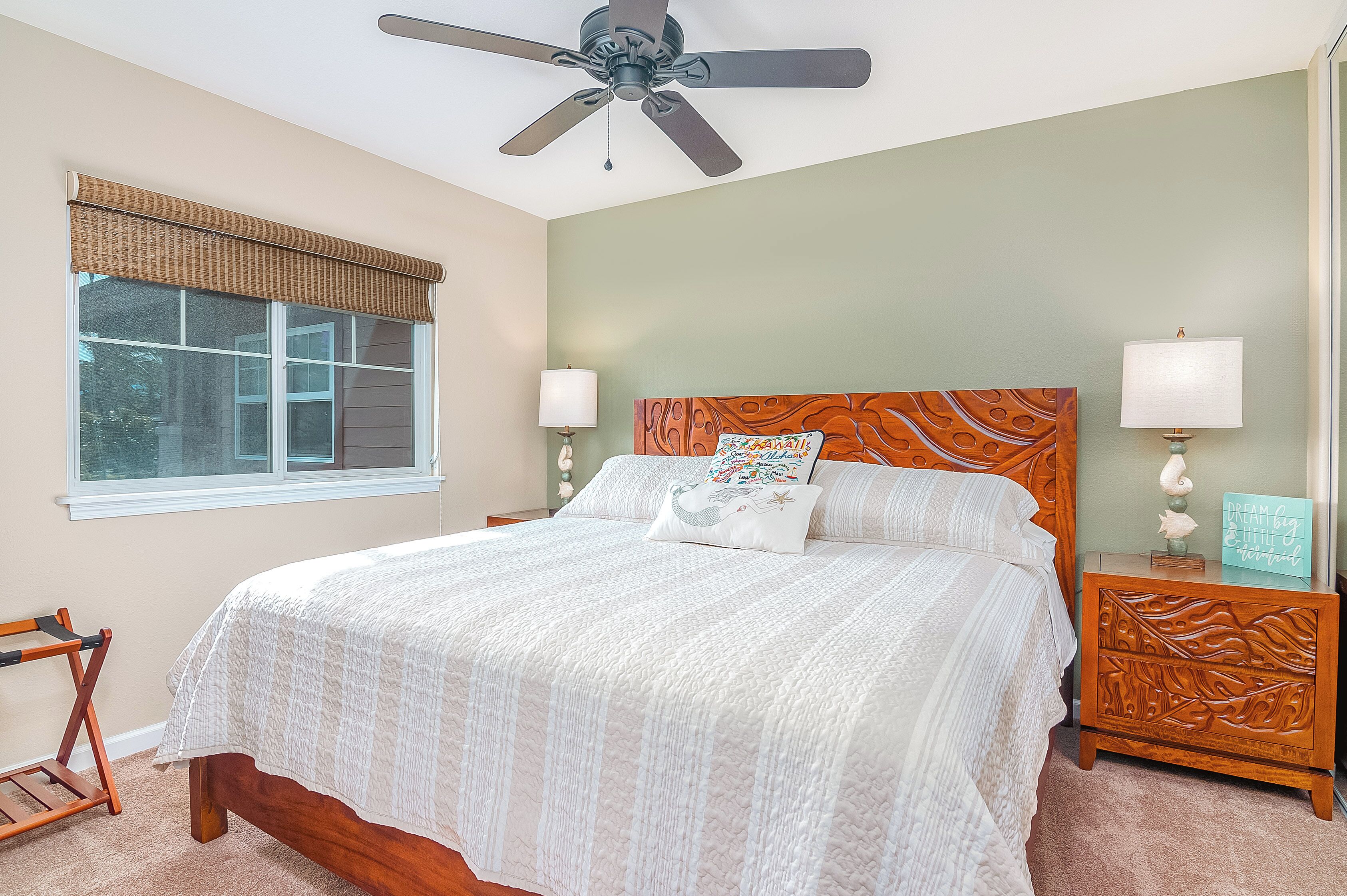 A bedroom with a bed, two bedside tables, a ceiling fan, and a window with blinds.