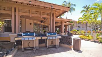 An outdoor patio with two barbecue grills, a trash can, and a stone planter.