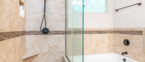 A modern bathroom with a glass-enclosed shower, a freestanding bathtub, and a window with a view.