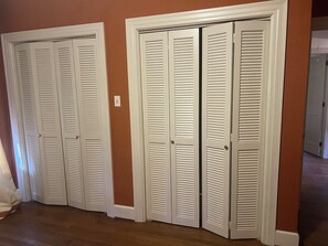 A hallway with three white louvered closets against a brown wall. - Villa Home (Goldsboro)
