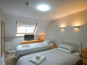 A bedroom with two beds, a TV, a window, and a ceiling light.