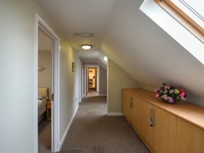 A narrow hallway with a sloped ceiling, a wooden cabinet with drawers, and a skylight. - The Garden Lodge Flat - UK49415 (LLanteg, near Narbeth)