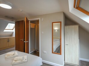 Une chambre d’hôtel avec un lit, une armoire, un miroir et une fenêtre de toit.