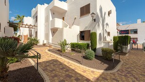 A white building with balconies, a paved courtyard, and a sign for "Baro". - Apartamento La Isla (Mar de Pulpi) (San Juan de los terreros)