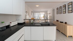 A modern kitchen with white cabinets, a black countertop, and a wooden sideboard. - Apartamento La Isla (Mar de Pulpi) (San Juan de los terreros)