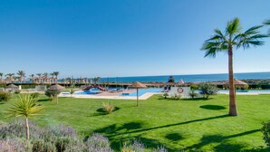 A resort with a swimming pool, palm trees, and a view of the sea. - Apartamento La Isla (Mar de Pulpi) (San Juan de los terreros)