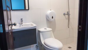 Un baño con inodoro blanco, lavamanos y ducha.