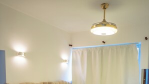 Habitación de hotel con dos camas, ventilador de techo y un amplio ventanal con cortinas.