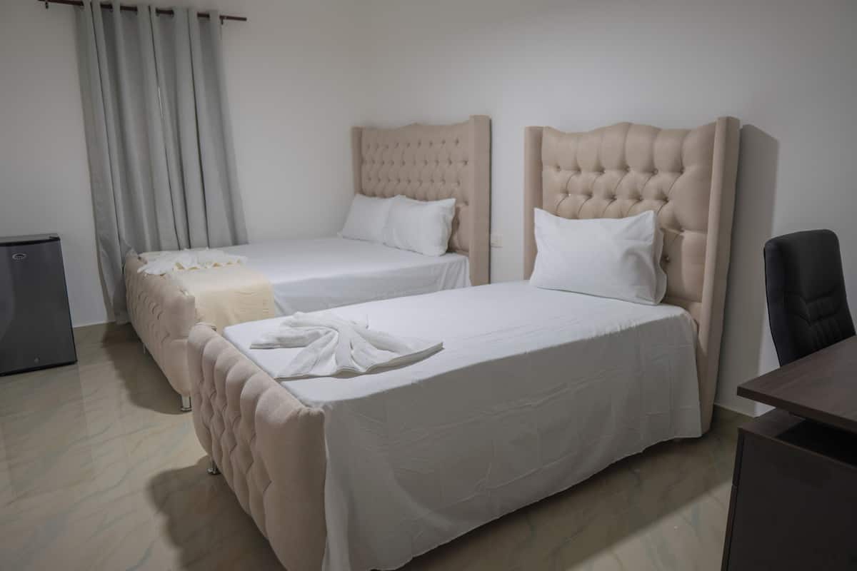 A hotel room with two beds, a desk, and a chair.