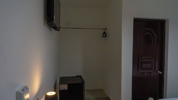 A narrow hallway with a door on the right, a small box on the left, and a light fixture on the wall.