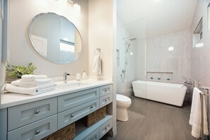 Un baño moderno con tocador, lavamanos, espejo y cabina de ducha con mampara de vidrio.