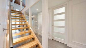 Eine Holztreppe mit Glastüren, die zu einem Raum mit einer weißen Tür und Blick auf einen Flur führen.
