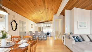 Ein Essbereich mit Holztisch, gedecktem Tisch für eine Mahlzeit, einer Couch und einer Küche im Hintergrund.