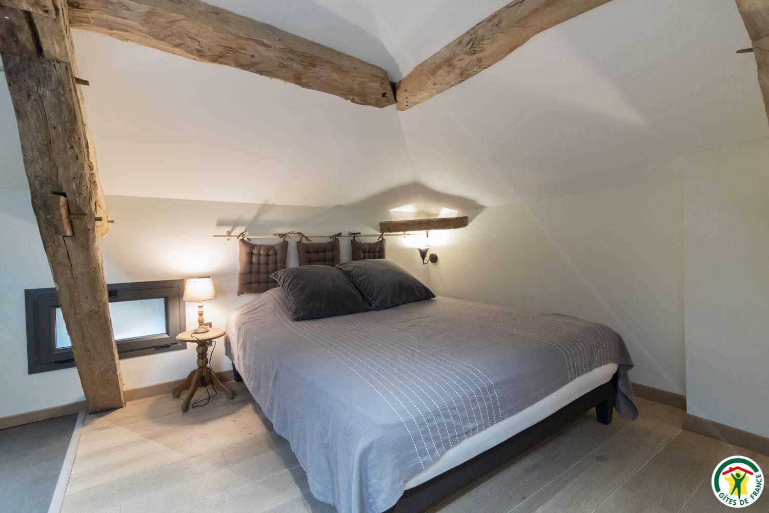 A bedroom with a bed, a nightstand, a lamp, and a window.
