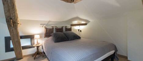 A bedroom with a bed, a nightstand, a lamp, and a window.