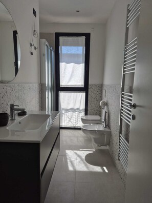 A modern bathroom with a large mirror, two sinks, a toilet, and a towel rack. - GRACE HOUSE - SANTA MONICA (Lido di Jesolo)