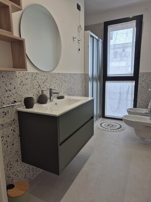 Un baño moderno con lavamanos independiente, un espejo grande y un inodoro.