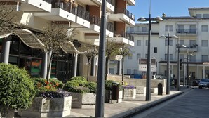 A multi-story residential building with balconies, outdoor lighting, and a paved street.