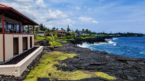 A coastal property with a modern building featuring large windows, a rock garden, and a view of the ocean. - Paradise Ocean Vista- Absolute Oceanfront gorgeous views, A/C & laundry! (Keaau)