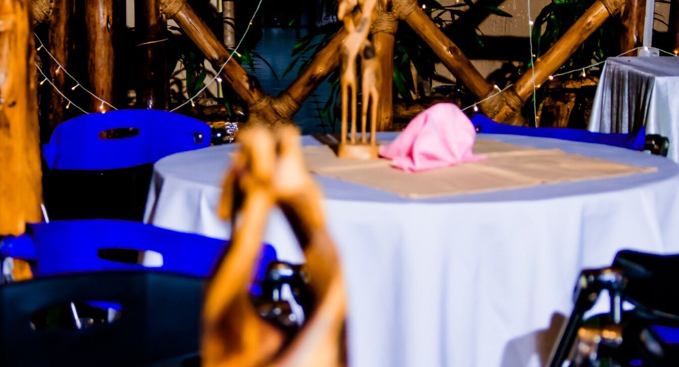 A round table with a white tablecloth, surrounded by blue chairs.