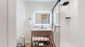 A modern bathroom with a glass shower enclosure, a white sink, and a mirror above it.