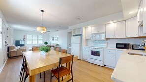 A modern kitchen with white cabinets, a wooden dining table, and a built-in oven.