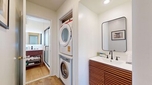 A laundry area with a washing machine, dryer, and a mirror above the sink.