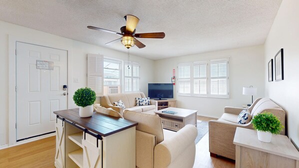 A modern living room with a ceiling fan, a TV, and a dining area with a table and chairs.
