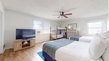 A bedroom with a TV, bunk beds, a ceiling fan, a dresser, and a mirror.