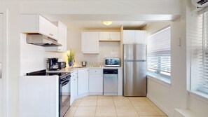 A modern kitchen with white cabinets, a stainless steel refrigerator, a microwave, and a dishwasher.
