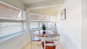A dining area with a round table, white chairs, and a potted plant.