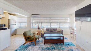 A modern living room with a sofa, armchair, coffee table, and a TV.