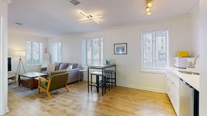 Una sala de estar moderna con un sofá, una mesa de comedor y una cocina con microondas.