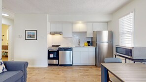 A modern kitchen with white cabinets, stainless steel appliances, and a dining area with a table and chairs.