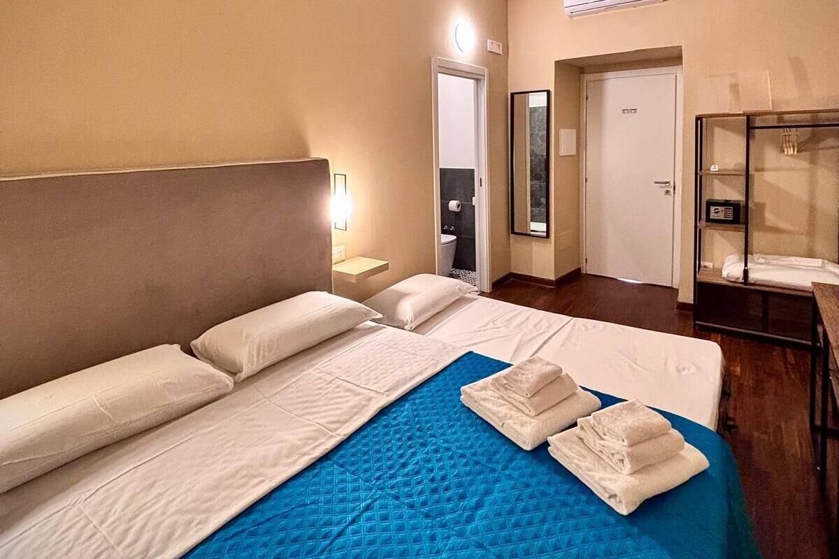 Habitación de hotel con una cama grande, un escritorio y una silla. Se ve un baño al fondo.