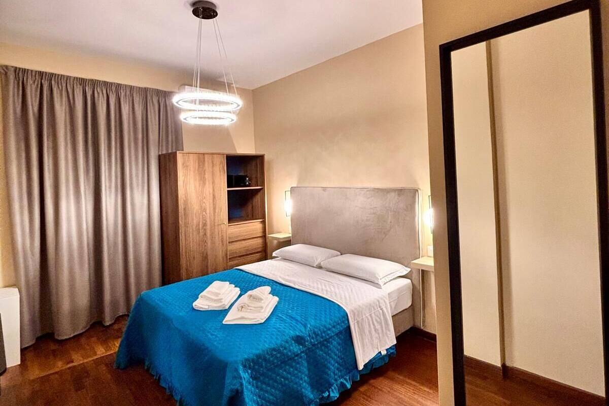 Una habitación de hotel con cama, armario, espejo y mesita de noche.