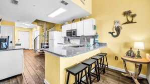 A kitchen with a central island, white cabinets, and a yellow accent wall.